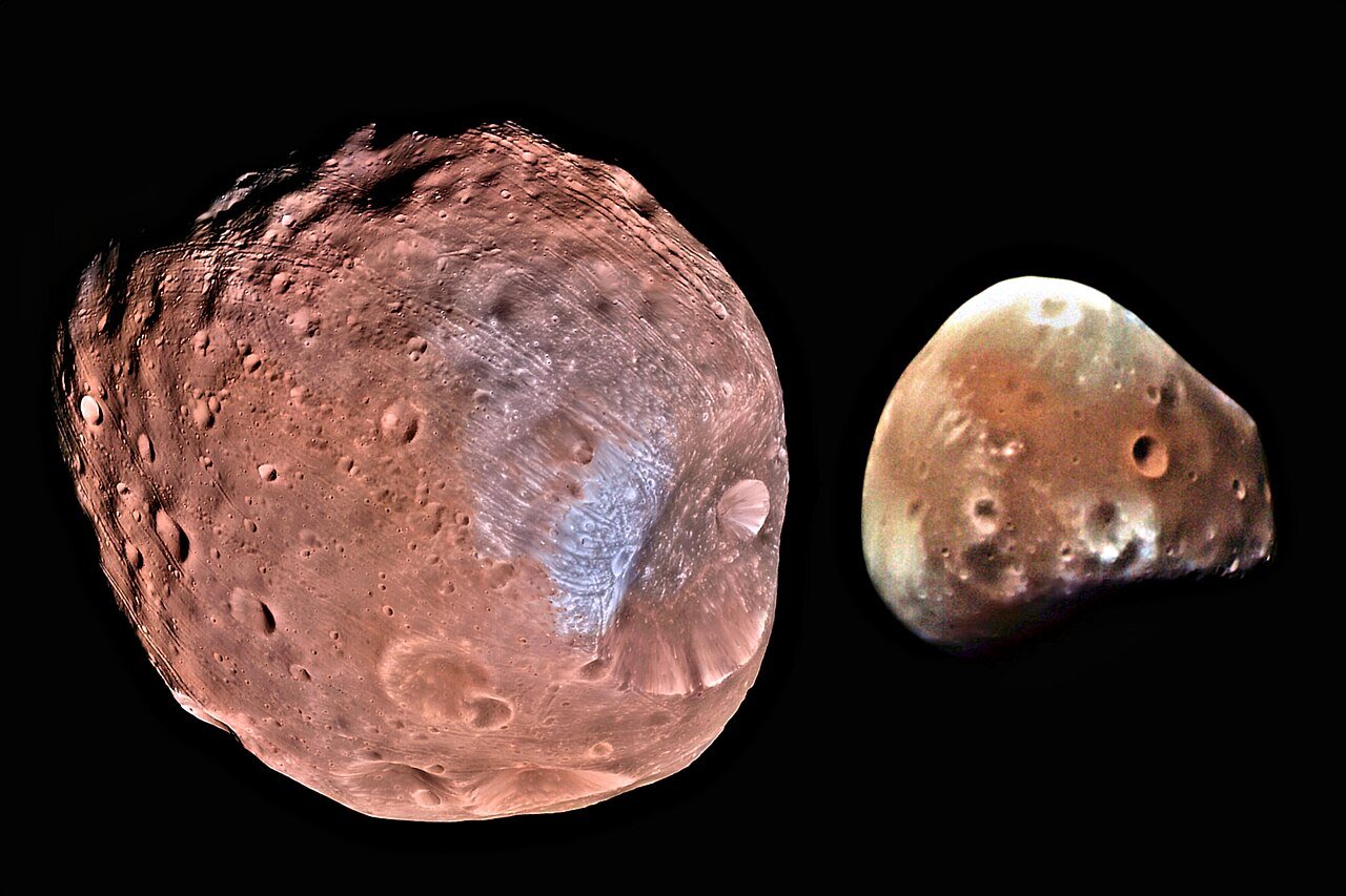 Fobos e Deimos, as duas luas de Marte, lado a lado sobre fundo preto: Fobos maior e cheia de crateras, Deimos menor e mais lisa