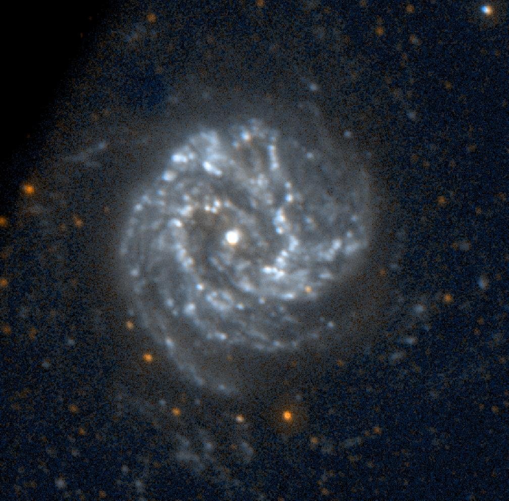 Galáxia espiral em tons de azul, com um ponto brilhante no centro, braços de estrelas em espiral e pontos de luz dispersos sobre um fundo escuro