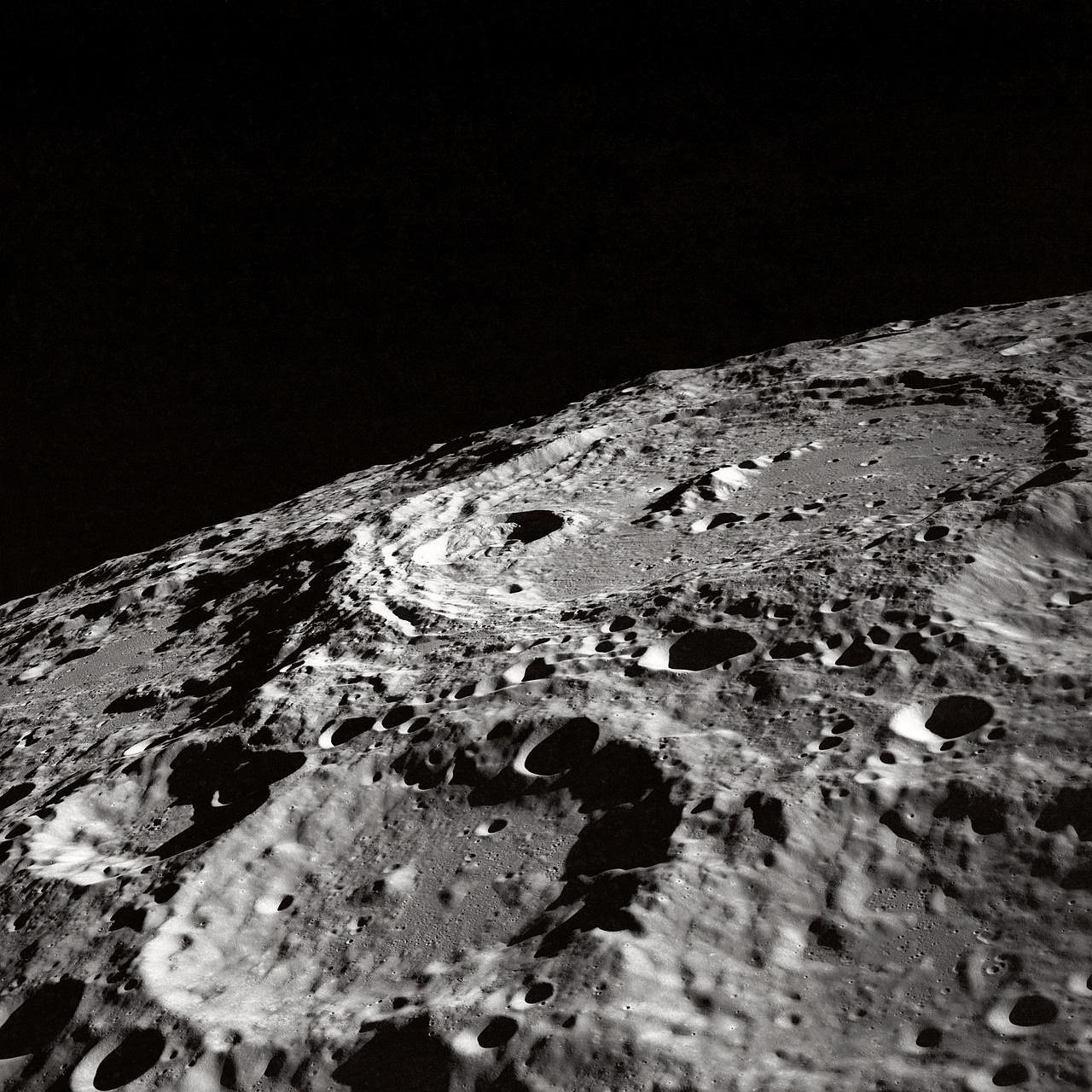 Foto aproximada da superfície da Lua mostrando uma cratera de impacto cercada por relevo irregular